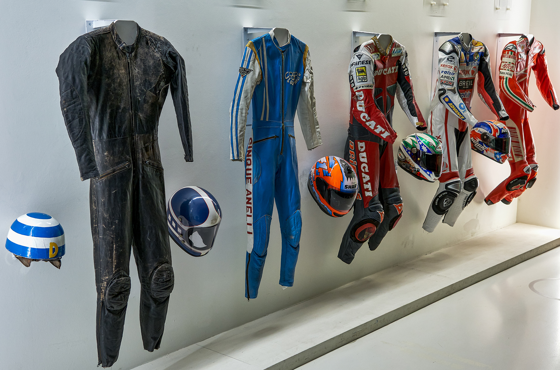 22 Progressi salvavita    OTTAVA CLASS
IL BACCHINO	ANDREA LAMBARDI
Questa immagine racconta in modo efficace levoluzione della sicurezza e del design nel mondo delle corse motociclistiche. La disposizione in sequenza delle tute da gara, dai modelli pi a