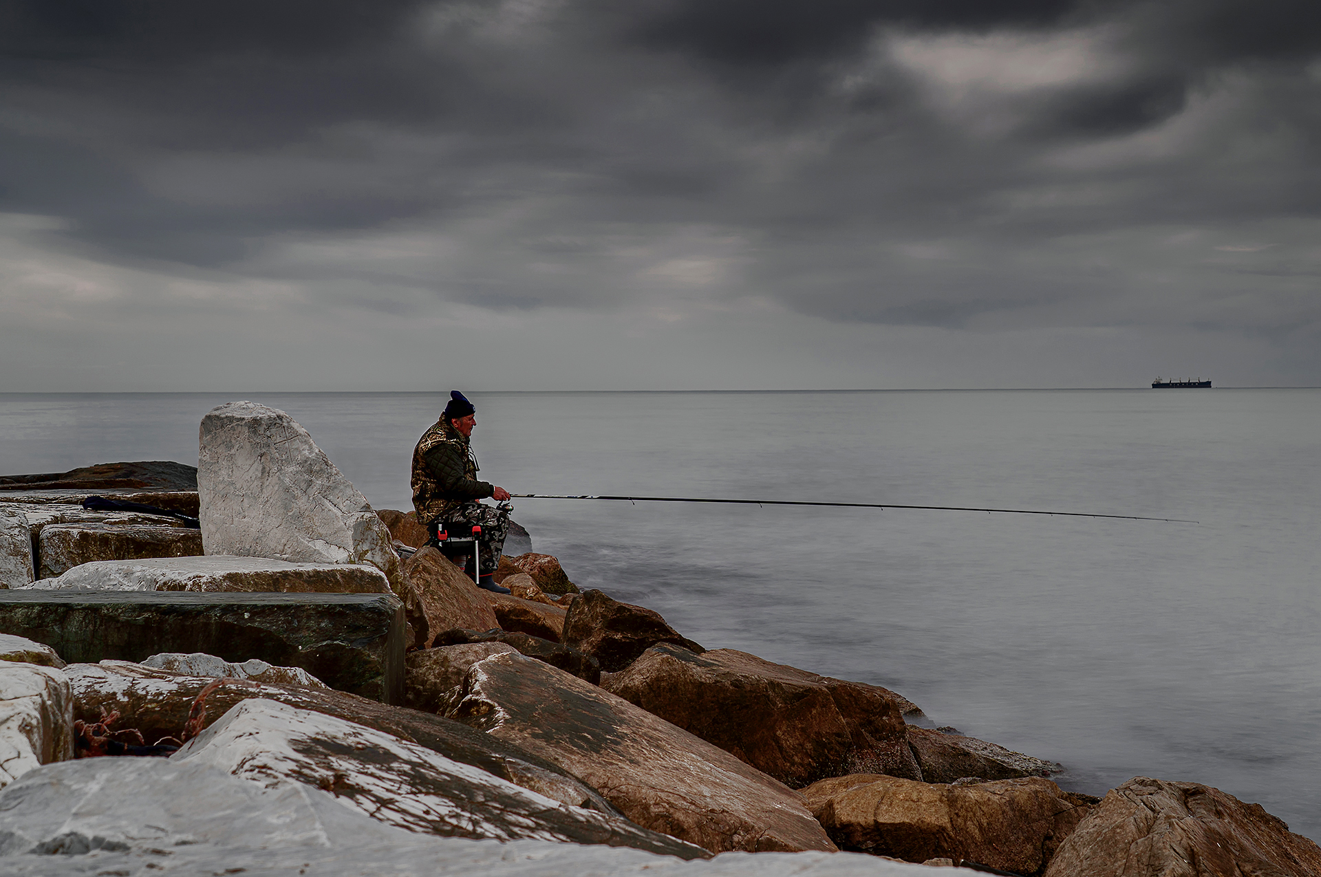28 - Il ritmo lento del pescatore SETTIMO CLASS
IMAGO CLUB PAOLO MOTTI

Un pescatore solitario, seduto sugli scogli con la canna da pesca protesa verso il mare calmo e sotto un cielo nuvoloso, attende con pazienza che un pesce abbocchi allamo. La pesca r